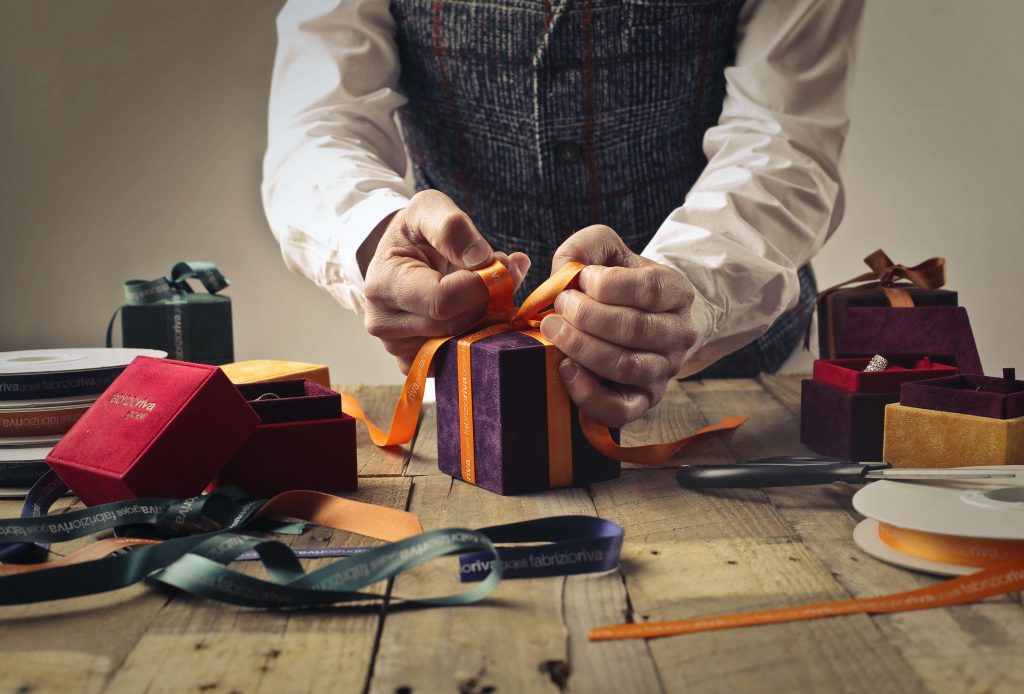 A man ties a bow on a gift box